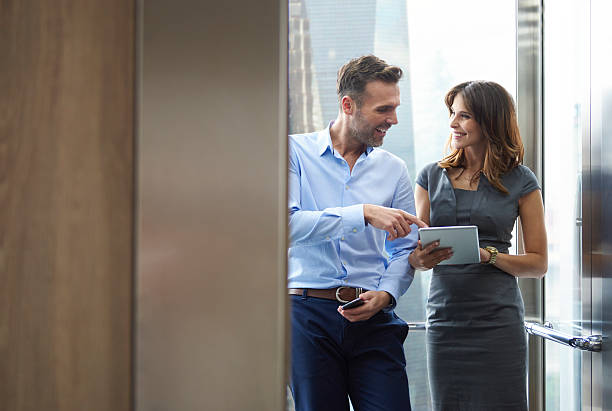 엘리베이터에서 비즈니스 남자와 여자 - business two people talking building exterior 뉴스 사진 이미지