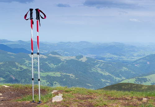 Pair of trekking poles made from three aluminum sections on a background of mountain ridges and valleys