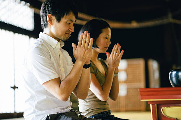 istock Japanese couple praying in a buddhist temple 597265828