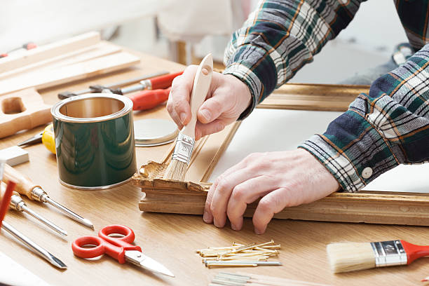 homem envernizamento uma moldura de madeira em casa - carpenter restoring furniture wood imagens e fotografias de stock