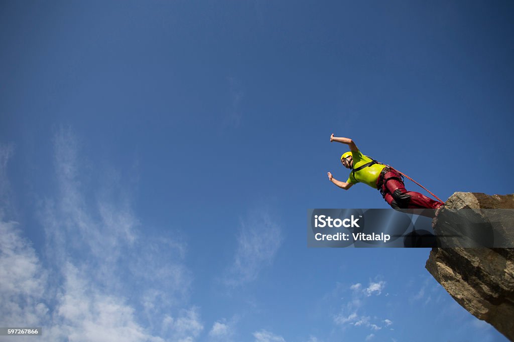 Jump off a cliff. Jump off a cliff into a canyon with a rope. Activity Stock Photo
