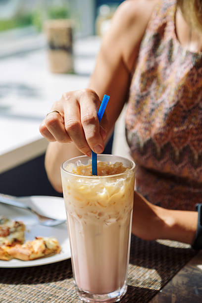 istock Female hand stirring cold drink in glass with straw 597269006