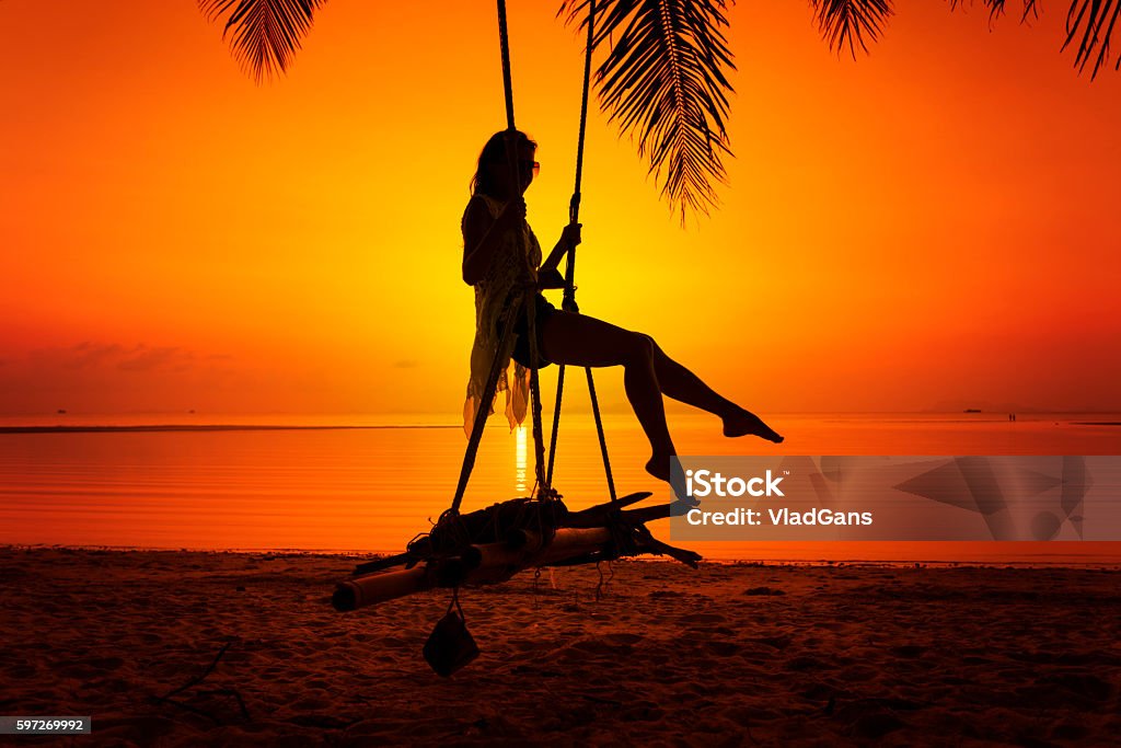 Woman sitting at tropical swing Activity Stock Photo