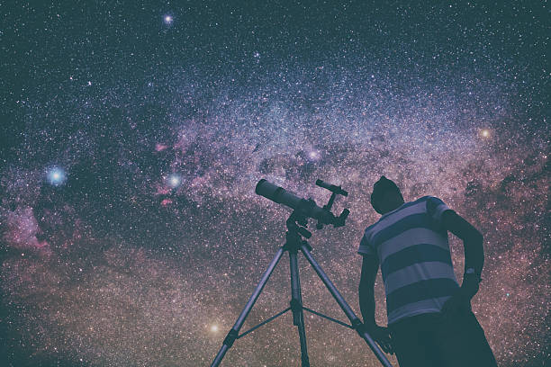 istock Man looking at the stars with telescope beside him. 597269996