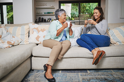 Shot of a young woman and her mother catching up on the sofa while drinking coffee
