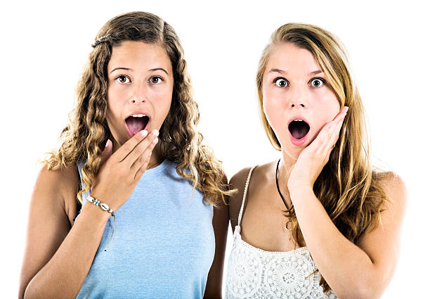 two pretty teenagers gasping in wide-eyed shock - gasping color image hands covering mouth staring imagens e fotografias de stock