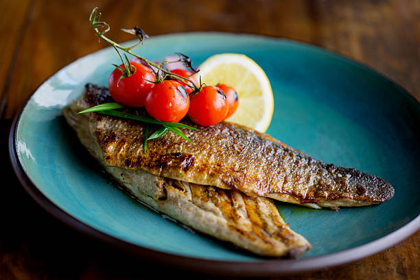 Freshly grilled trout Freshly grilled trout, garnished with cherry tomato and lemon slices trout stock pictures, royalty-free photos & images
