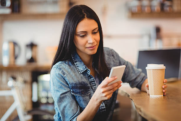 istock Woman using mobile phone at office cafeteria 597630756