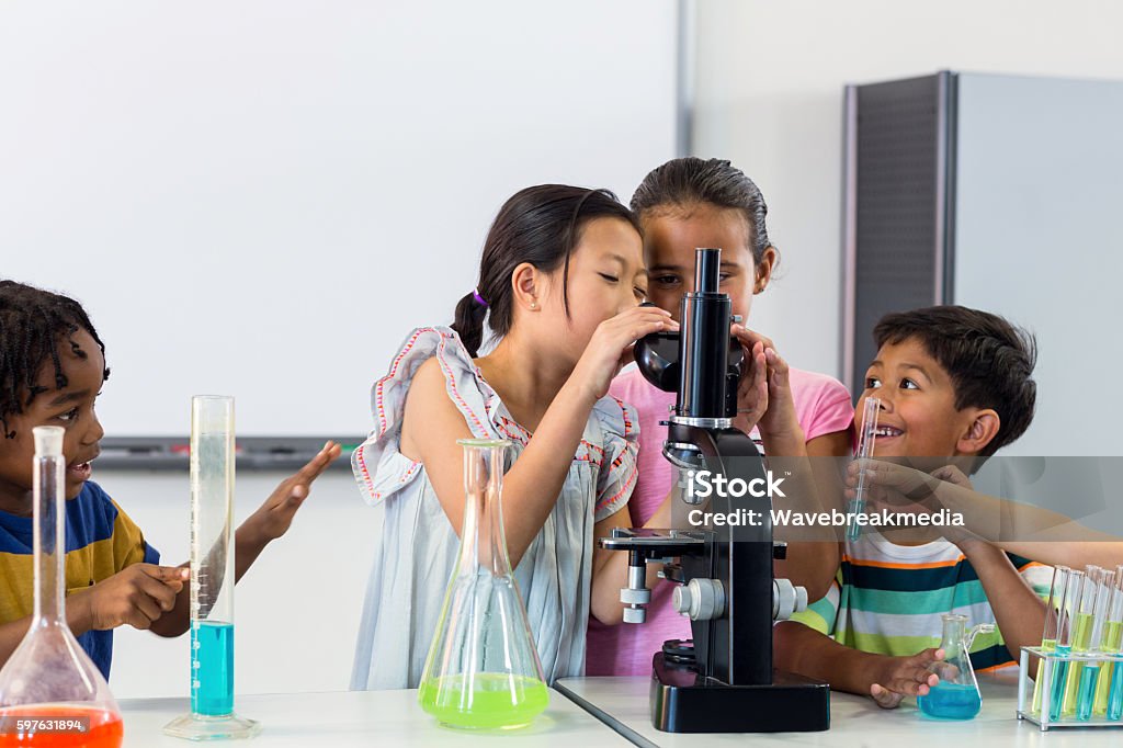 Children looking in microscope Schoolchildren looking in microscope in lab Child Stock Photo