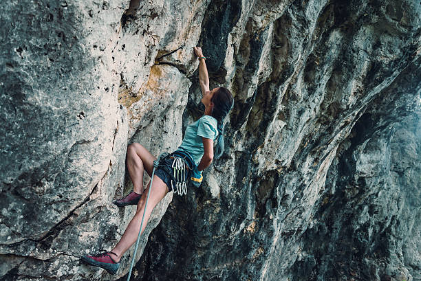 istock Woman climbing the rock wall 597636194