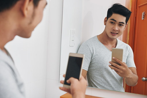 Attractive Asian man taking selfie in the mirror