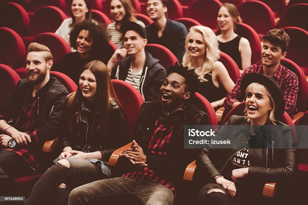 Multi ethnic group of people in the movie theater Multi ethnic group of young people in the cinema or theater, watching, laughing.  Movie Theater Stock Photo