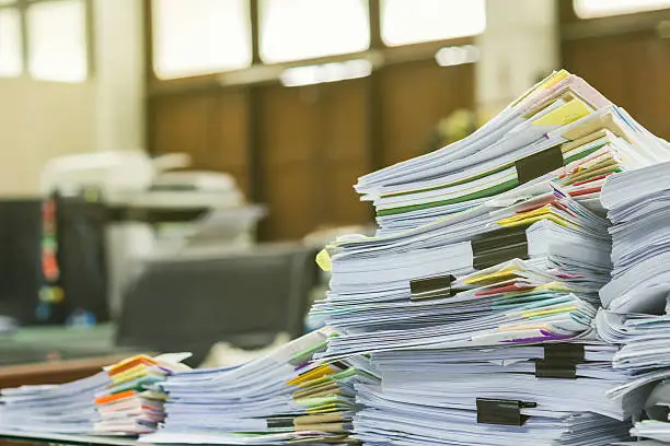 Photo of Pile of documents on desk at workplace