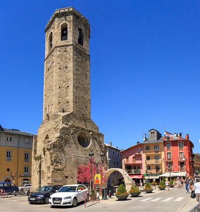 Puigcerda, Spain - July 17, 2016: Torre del Campanar (12th century) on Placa Santa Maria on a bright, cloudless sunday in summer. Puigcerda is capital of the Catalan comarca of Cerdanya on the border with France, and a summer and winter tourist destination