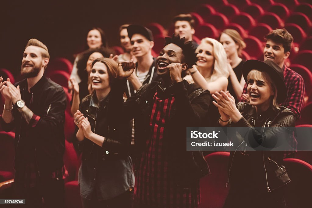 Multi ethnic group of people in the theater Multi ethnic group of young people in the theater, clapping hands. Audience Stock Photo