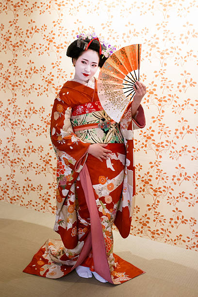 chica maiko posando con ventilador plegable japonés - geisha fotografías e imágenes de stock
