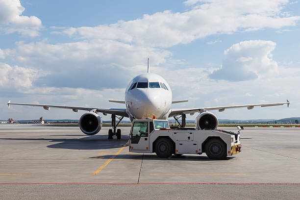 istock Vehicles towing white modern aircraft on parking lot 597641190