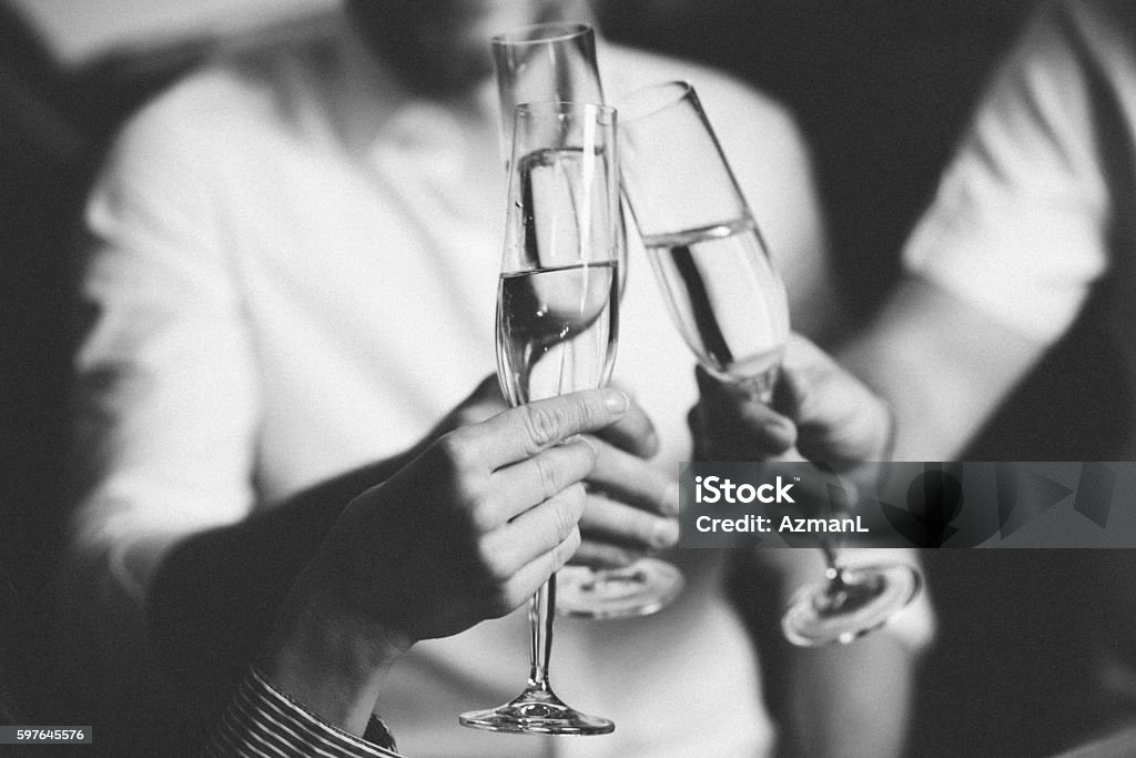 Cheers Three businesspeople sitting in a coffee shop and toasting with champagne in the evening. Formalwear Stock Photo