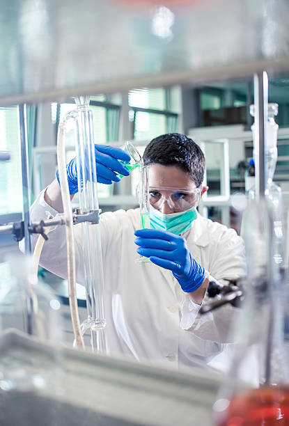 istock Scientist pouring a reagent into a measuring cylinder 597645754