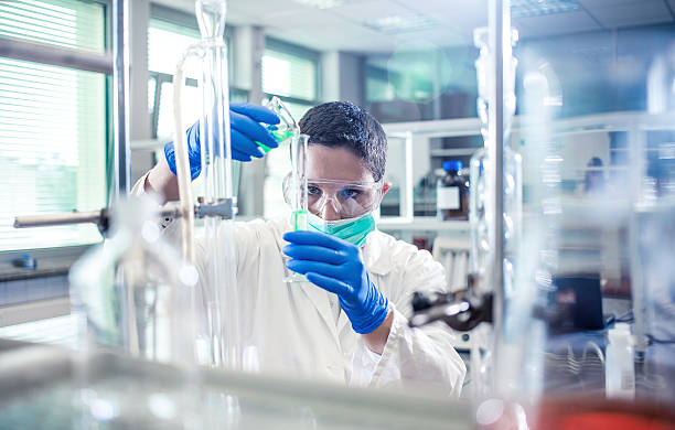istock Scientist pouring a reagent into a measuring cylinder 597645756