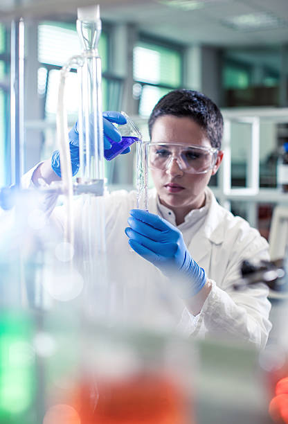 istock Scientist pouring a reagent into a measuring cylinder 597645758