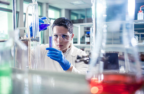 istock Scientist pouring a reagent into a measuring cylinder 597645760
