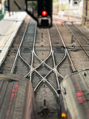 Two stationary trains in a station, with an 'X' shape created by crossing train tracks.
