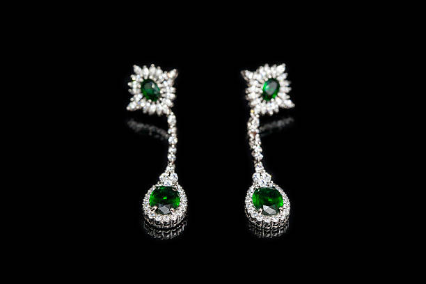 istock Earrings with green stones isolated on black, close-up 597650870