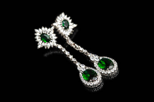 istock Earrings with green stones isolated on black, close-up 597650896