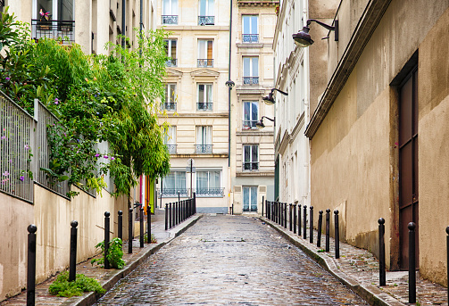 Paris Montmartre cobblestoned wet uphill street lined with apartment buildings.