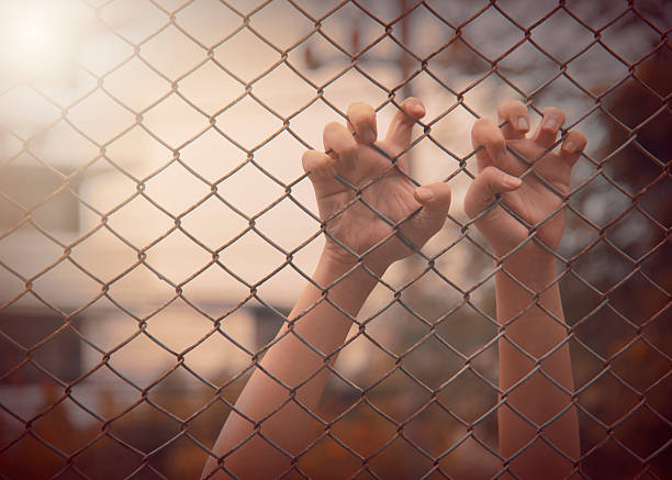 istock hand with metal fence,no freedom, 597653340