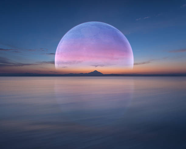 Pink planet like moon above the ocean and mountain Big beautiful planet over the sea horizon rises at dawn. Futuristic concept with copy space. planet space stock pictures, royalty-free photos & images