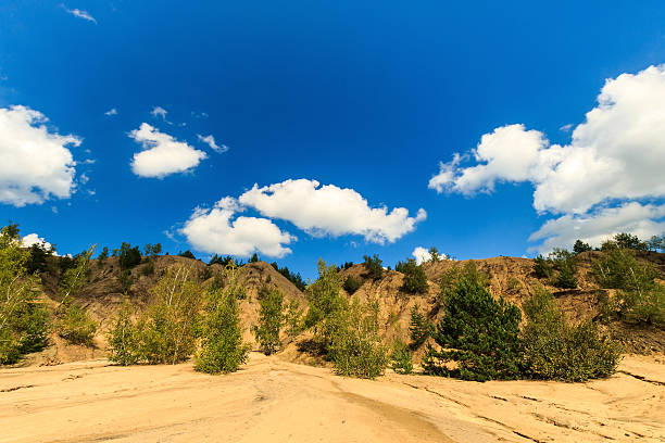 quarry with sandy beach,trees and hills with cloudly sky at summer season