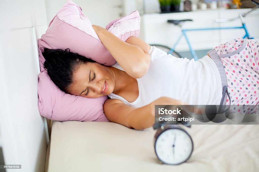 young woman trying not to wake up young woman trying not to her the alarm clock Alarm Clock Stock Photo