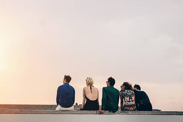 istock Friends sitting together on rooftop at sunset 597666198