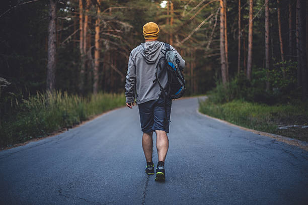 istock Male traveler with backpack walks forward by the road 597670760
