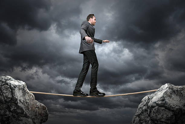 istock Businessman balancing on tightrope with stormy day 597672094