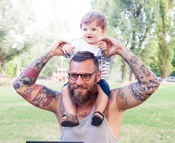 tattooed dad have fun with his son and laptop stock photo