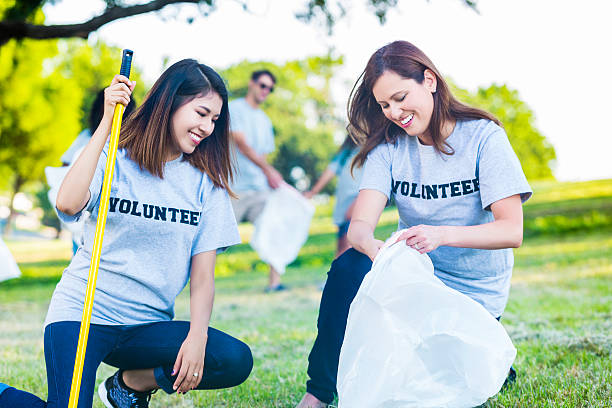 istock Diverse friends help pick up trash in community park 597674192