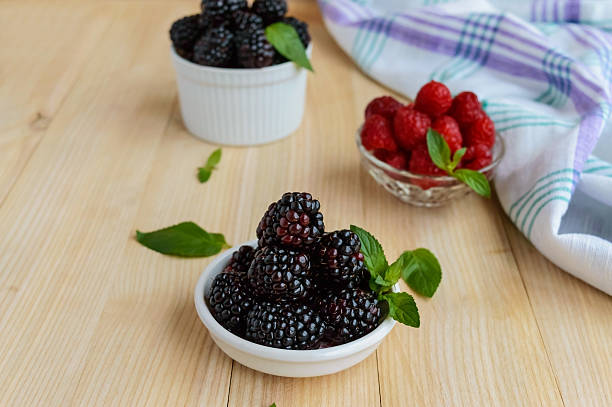 istock Freshly picked blackberries and raspberries on a light wooden background 597674318