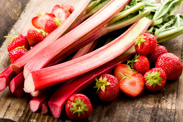 Rhubarb and strawberries Fresh rhubarb and strawberries on a wooden underground rhubarb stock pictures, royalty-free photos & images