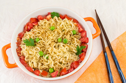 Prepared noodles with tomato and peas in a bowl
