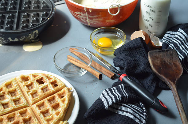 istock Waffle iron, cinnamon sticks, bowl of batter, utensils 597930254