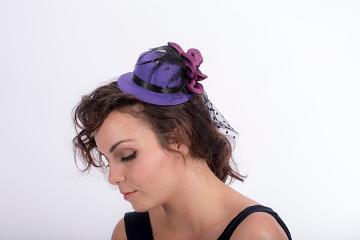 young woman in purple fascinator pensively looking down