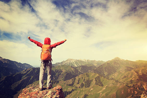istock successful young woman backpacker open arms on mountain peak 597932840