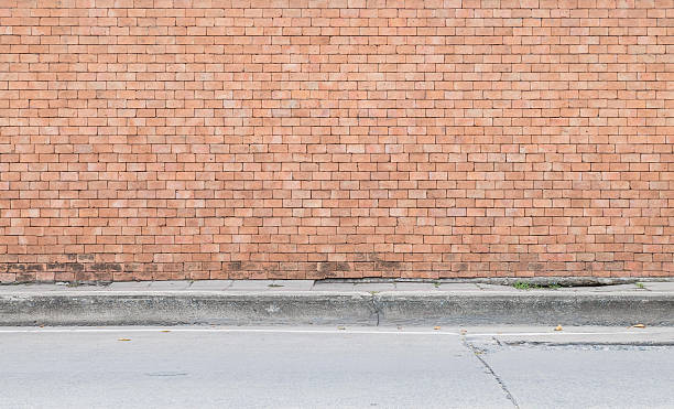 istock Closeup brown brick wall with street floor textured background 597935982