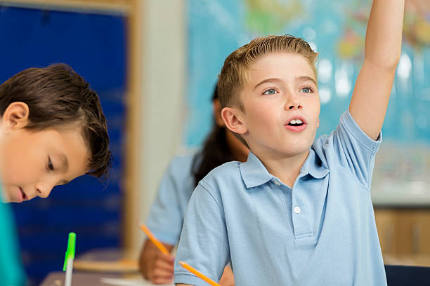 istock Cute Caucasian boy raises hand to answer question in class 597936360