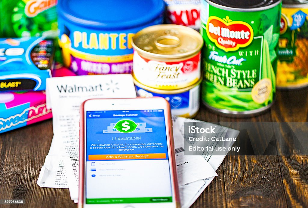 Walmart Savings Catcher App on iPhone screen and assorted groceries Peyton, Colorado, USA - August 30, 2016: A horizontal studio shot of an Apple iPhone 6 plus with the Walmart Savings Catcher app on the screen. Behind the phone are receipts from Walmart and an assortment of groceries purchased at the store. Wal-mart Stock Photo