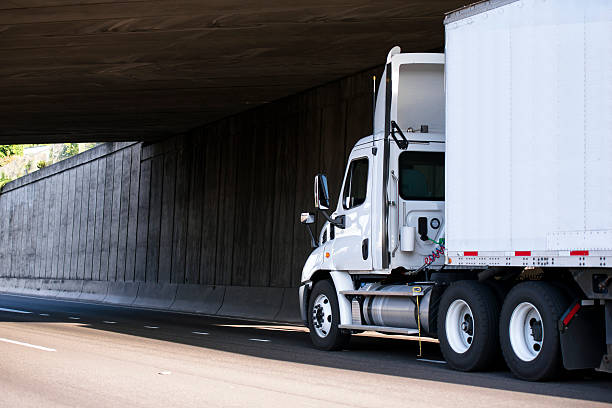 istock Day cab Semi truck going on road under bridge 597937436