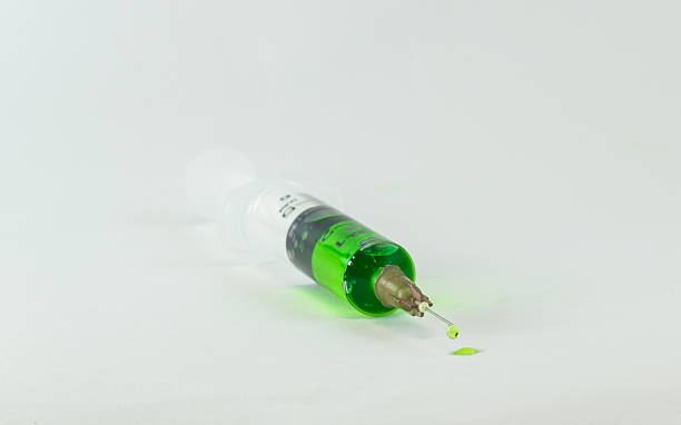 istock plastic medical syringe with green liquid emerging out 597938086